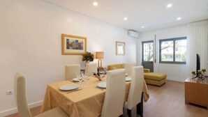 A dining area with a table set for four, a sofa, and a television. - Anna´s Flats | Jardim do Morro by HostWise (Vila Nova de Gaia)