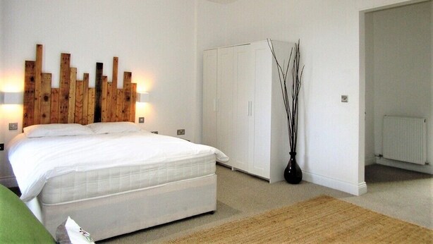 A bedroom with a bed, a wardrobe, and a radiator. - Large Private Double En-suite - 5 (London)