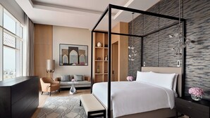 Un dormitorio moderno con cama con dosel, un sofá, un escritorio y un ventanal grande.