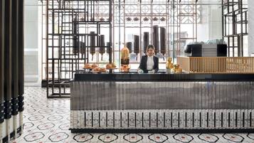 A modern interior with a bar area, geometric patterned floor, and a city view through large windows.