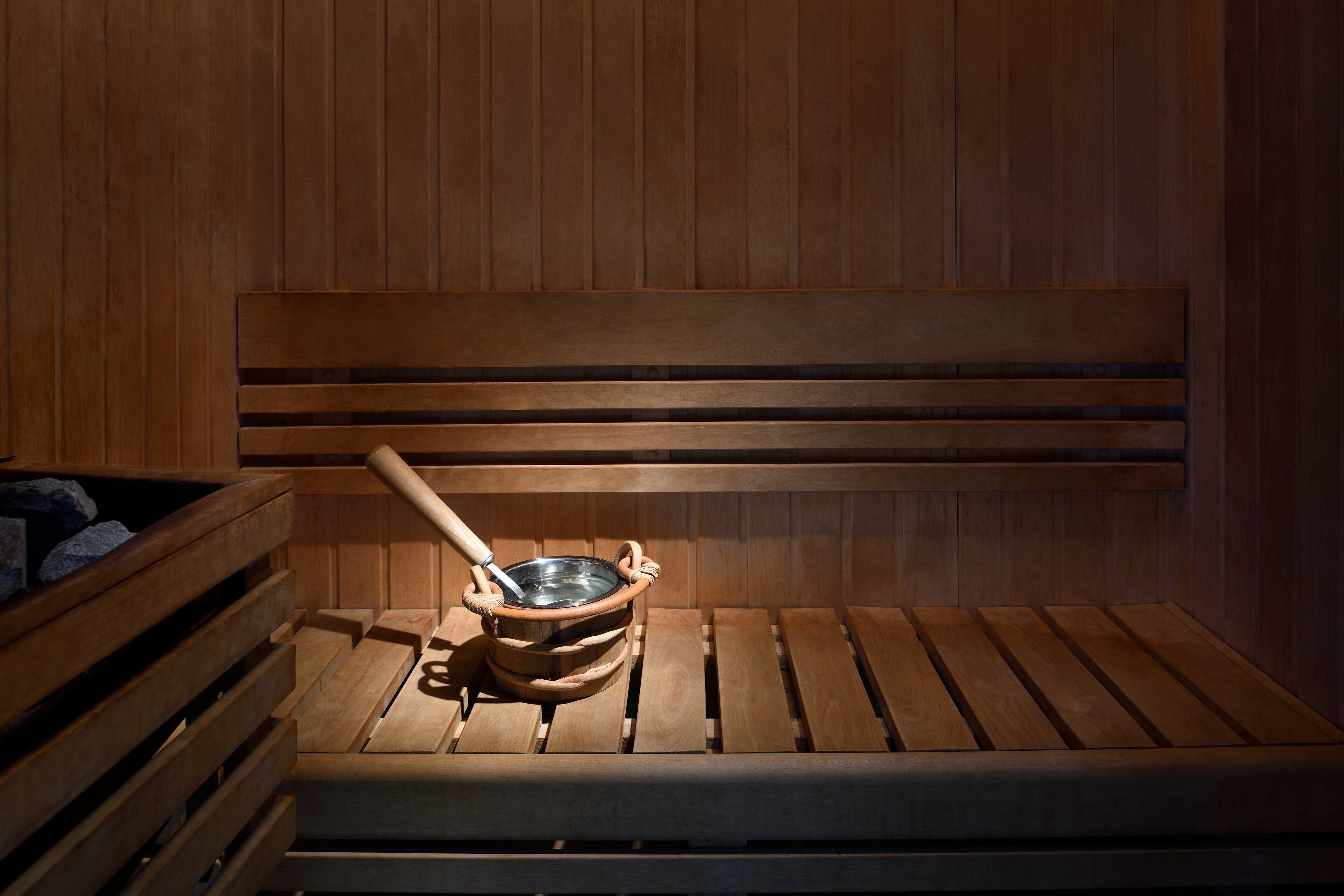 Una sauna de madera con bancos y un cubo de madera y una cuchara.