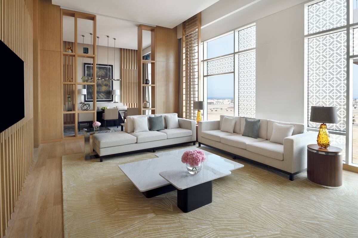 Un salon moderne avec deux canapés, une table basse et un téléviseur. Une grande fenêtre offre une vue sur le désert.
