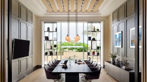 Un espace repas moderne avec une longue table, des chaises et un téléviseur placé sur le côté gauche.