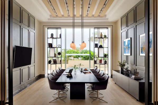 Un comedor moderno con una mesa larga, sillas y un televisor a la izquierda.