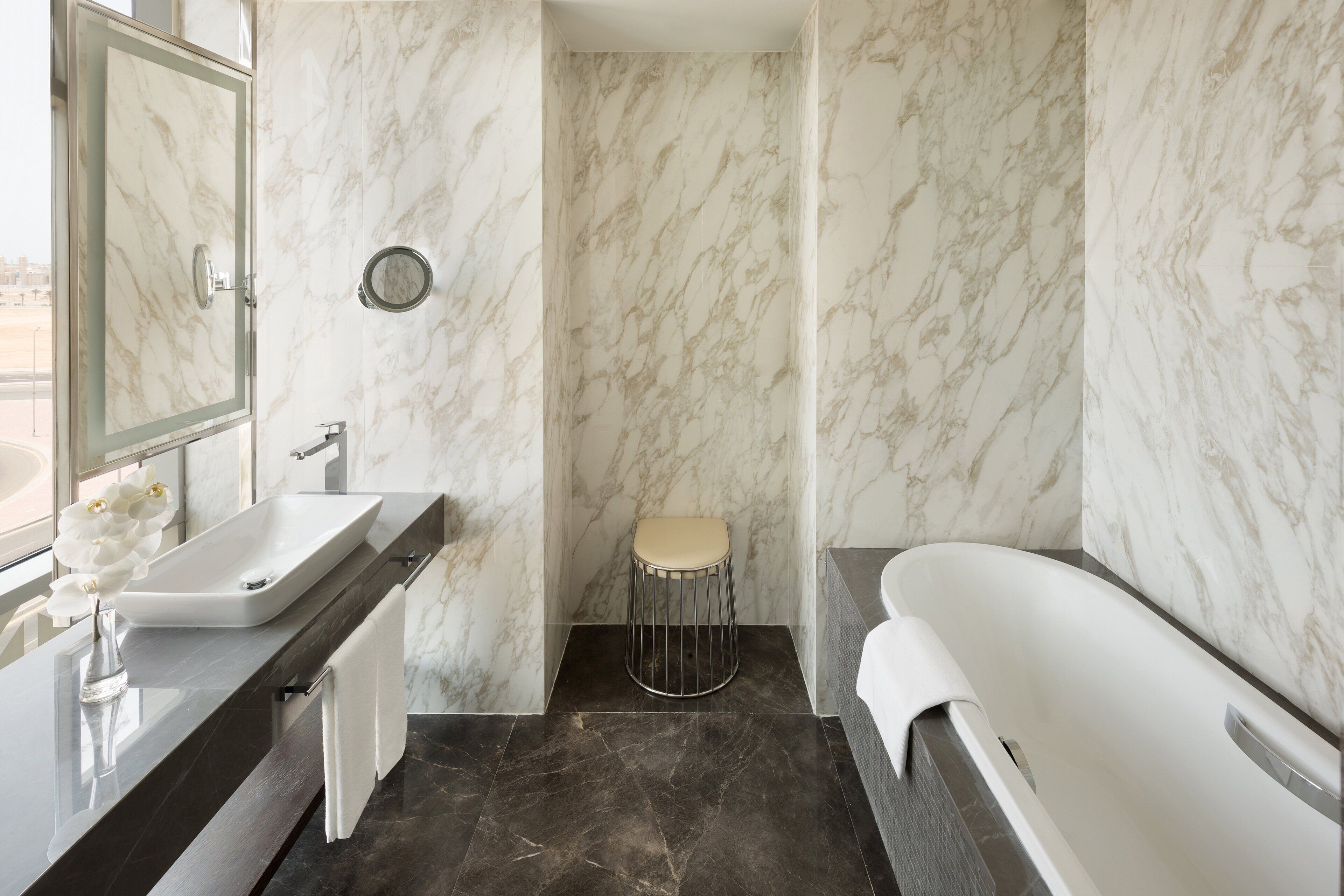A bathroom with a marble wall, a white sink, a toilet, and a bathtub.