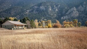 A house with a porch, surrounded by a field and mountains in the background. - Evergreen Lane Getaway · River Views and Front Porch Sitting in Paradise (Livingston)