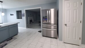 A modern kitchen with a double door refrigerator, a marble-tiled floor, and a light blue wall. - Stone Mountain Escape 4 Bedroom Private Home (Stone Mountain)
