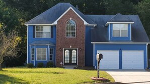 A two-story house with a blue exterior, a brick section, and a garage. - Stone Mountain Escape 4 Bedroom Private Home (Stone Mountain)