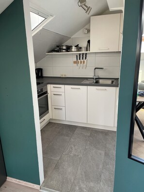 A compact kitchen with white cabinets, a built-in oven, and a window above the sink.
