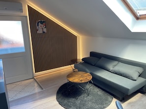 A modern living room with a sofa, a round coffee table, and a vertical wooden slat wall.