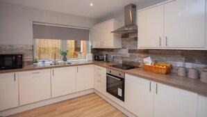 Een moderne keuken met witte kastjes, een magnetron, een broodrooster en een fornuis.