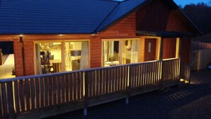 Een houten chalet met een balkon, grote ramen en een schuin dak.