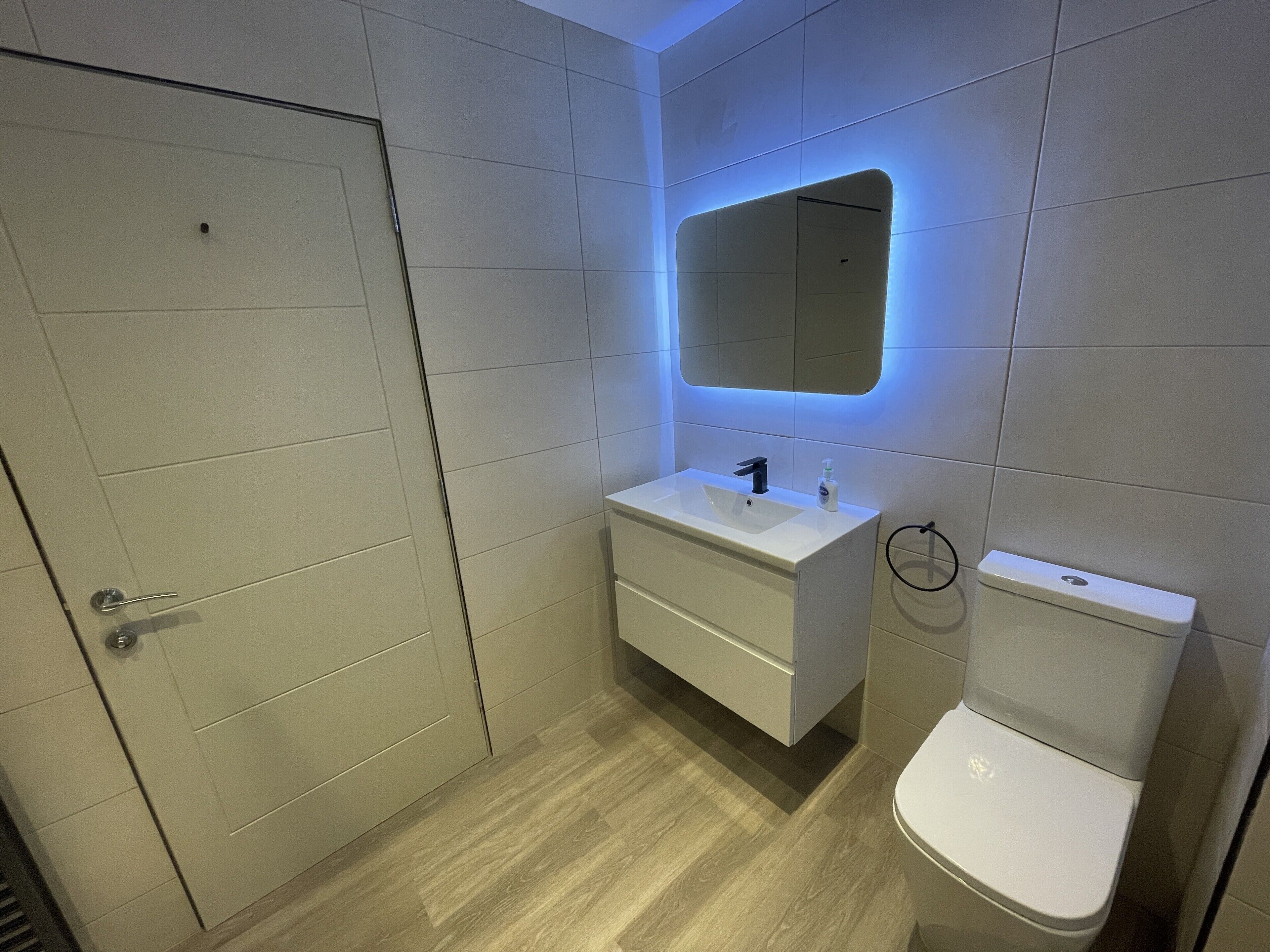 A modern bathroom with a white sink, mirror, and toilet.