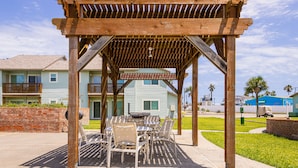 A wooden pergola with a sign stating "No Smoking and Parking Permits Required" over a patio area with tables and chairs. - Second Floor Condo With Bay View, Shared Pool, Pet Friendly (Port Aransas)