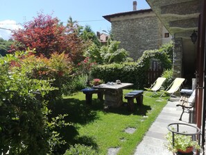 A stone building with a stone staircase leading to a covered patio area. - Apartment in an old barn, private garden overlooking the village (Plesio)