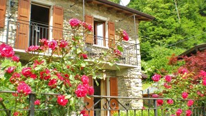 Un bâtiment en pierre avec des volets en bois, un balcon et une antenne parabolique.