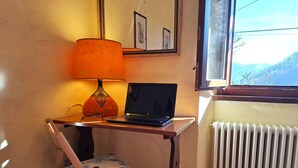 Un petit espace de travail comprenant un ordinateur portable, une lampe et une chaise.
