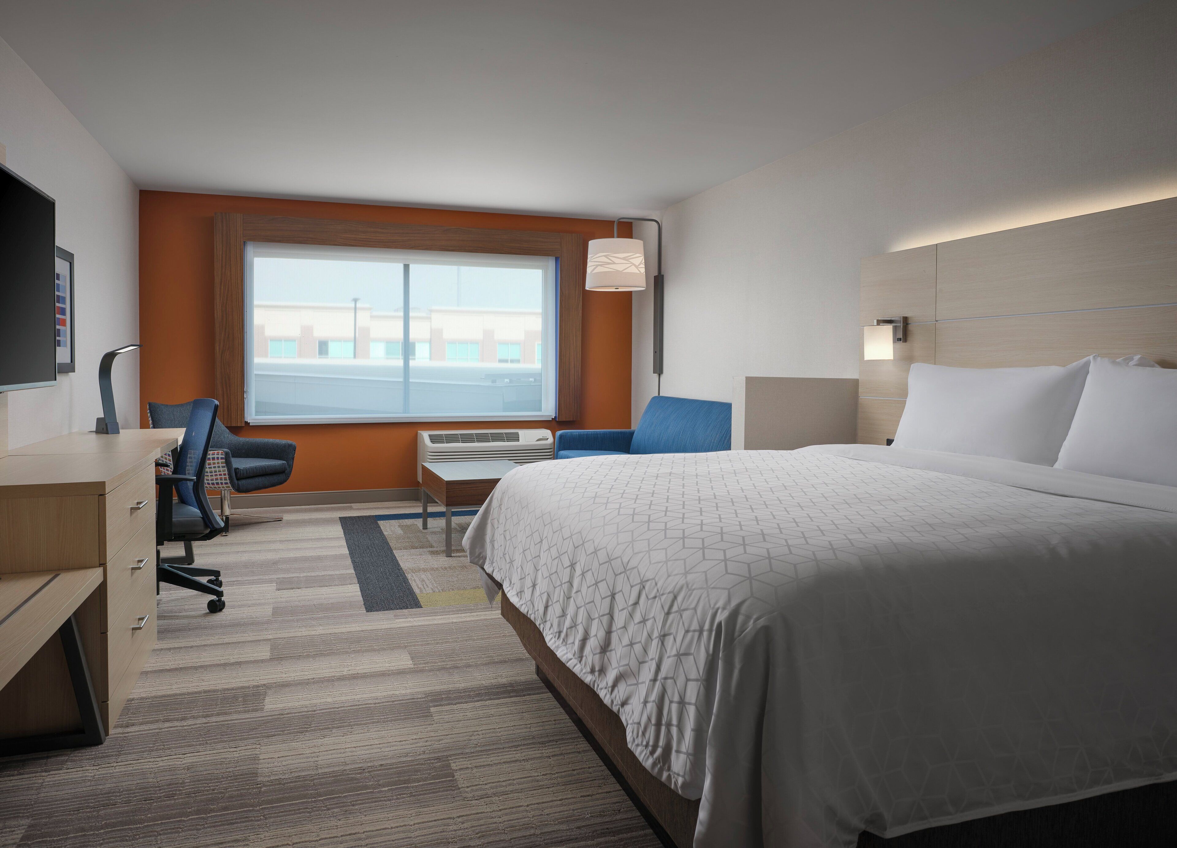 Ein Hotelzimmer mit Bett, Schreibtisch, Stuhl und einem großen Fenster.