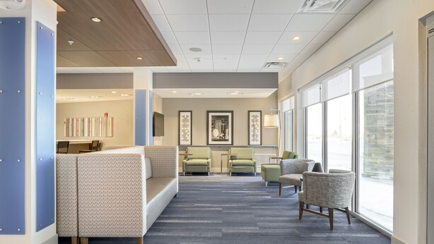 A modern lobby with a reception desk, seating area, and large windows.