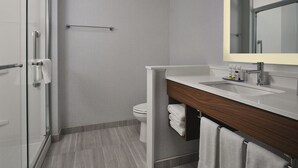 A modern bathroom with a glass shower enclosure, a white toilet, and a vanity with a wooden countertop.