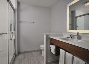 Et moderne badeværelse med brusekabine i glas, et hvidt toilet og en vask med træbordplade.