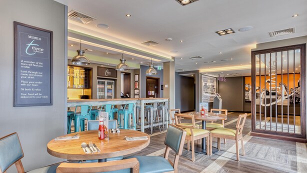 Un restaurante moderno con mesas redondas, asientos de bar y una pizarra con el menú.