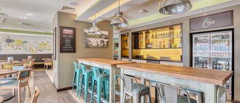 Een restaurant met een bar, hoge zitjes en een menubord.