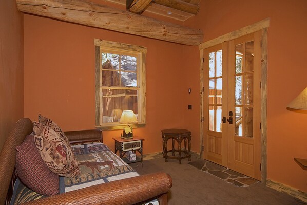 A cozy bedroom with a bed, a nightstand, a lamp, and a wooden door.