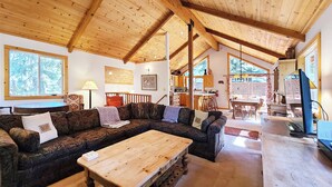 A spacious living area with a wooden ceiling, a large sofa, a coffee table, and a kitchen in the background. - Rosemor - 3 bedroom, 2 bath, fenced in back yard! Walk to Lake! (Tahoe City)