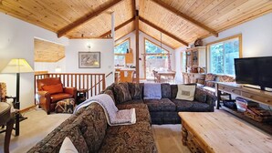 A cozy living room with wooden ceilings, a large sectional sofa, a wooden coffee table, and a television. - Rosemor - 3 bedroom, 2 bath, fenced in back yard! Walk to Lake! (Tahoe City)