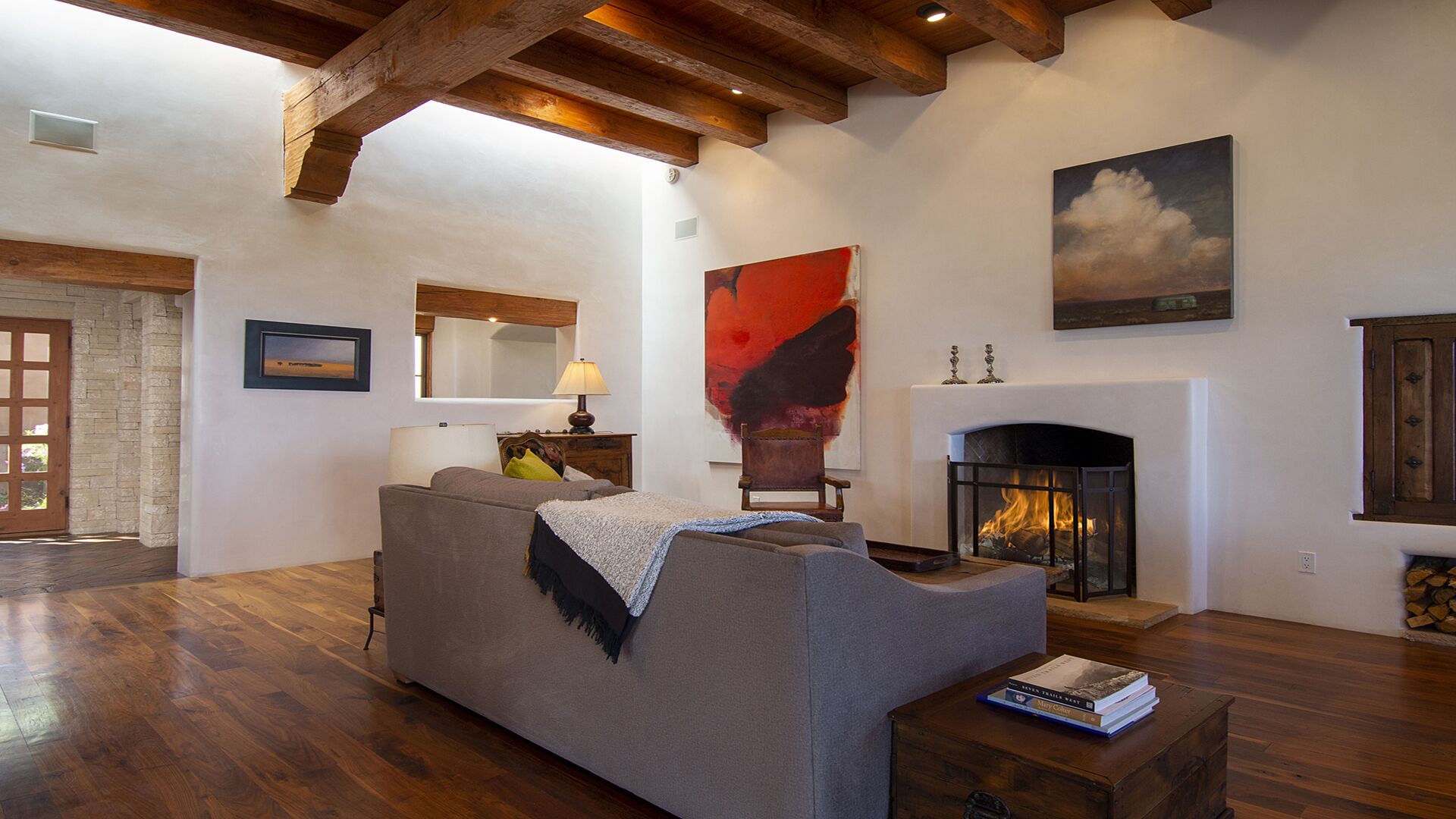 Uma sala de estar com lareira, vigas de madeira, um sofá e um quadro.