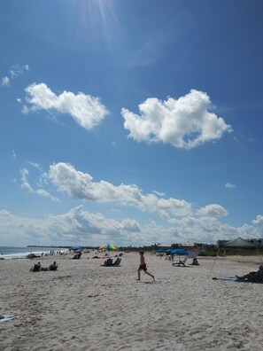 A beach with people, umbrellas, and beach chairs.