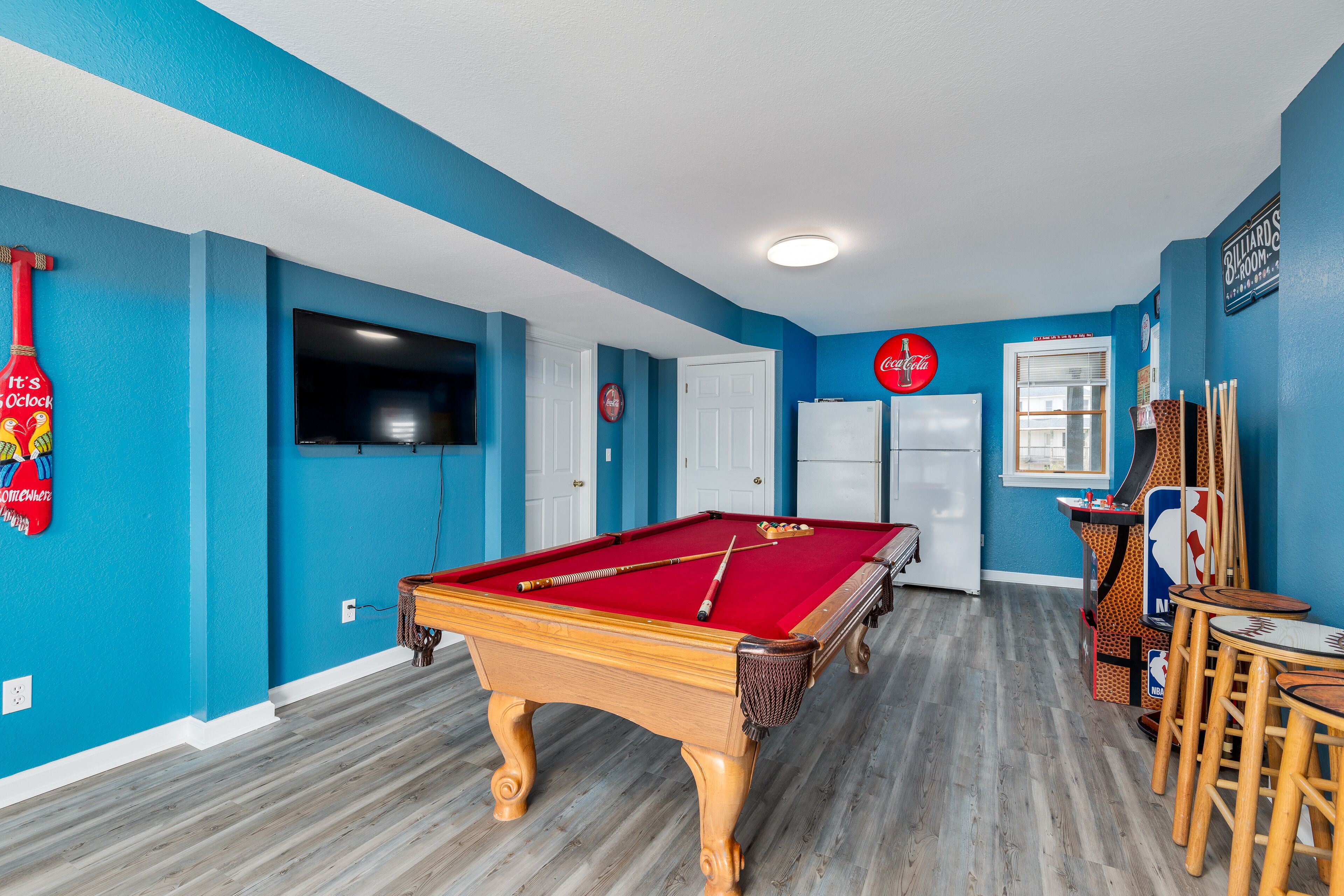 A pool table in a room with blue walls and wooden flooring.