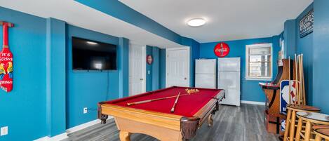 A pool table in a room with blue walls and wooden flooring.