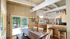 A spacious kitchen with wooden cabinets, a dining area with a large table and chairs, and a view of the outdoors through large windows. - Chambers Delight House - Chambers beach & pool & tennis * 4 bedroom, 2.5 bath (Tahoma)
