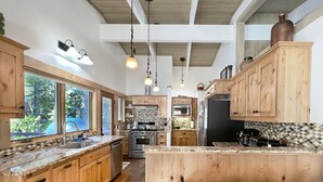 A spacious kitchen with wooden cabinets, a large island, and a view of the outdoors. - Chambers Delight House - Chambers beach & pool & tennis * 4 bedroom, 2.5 bath (Tahoma)