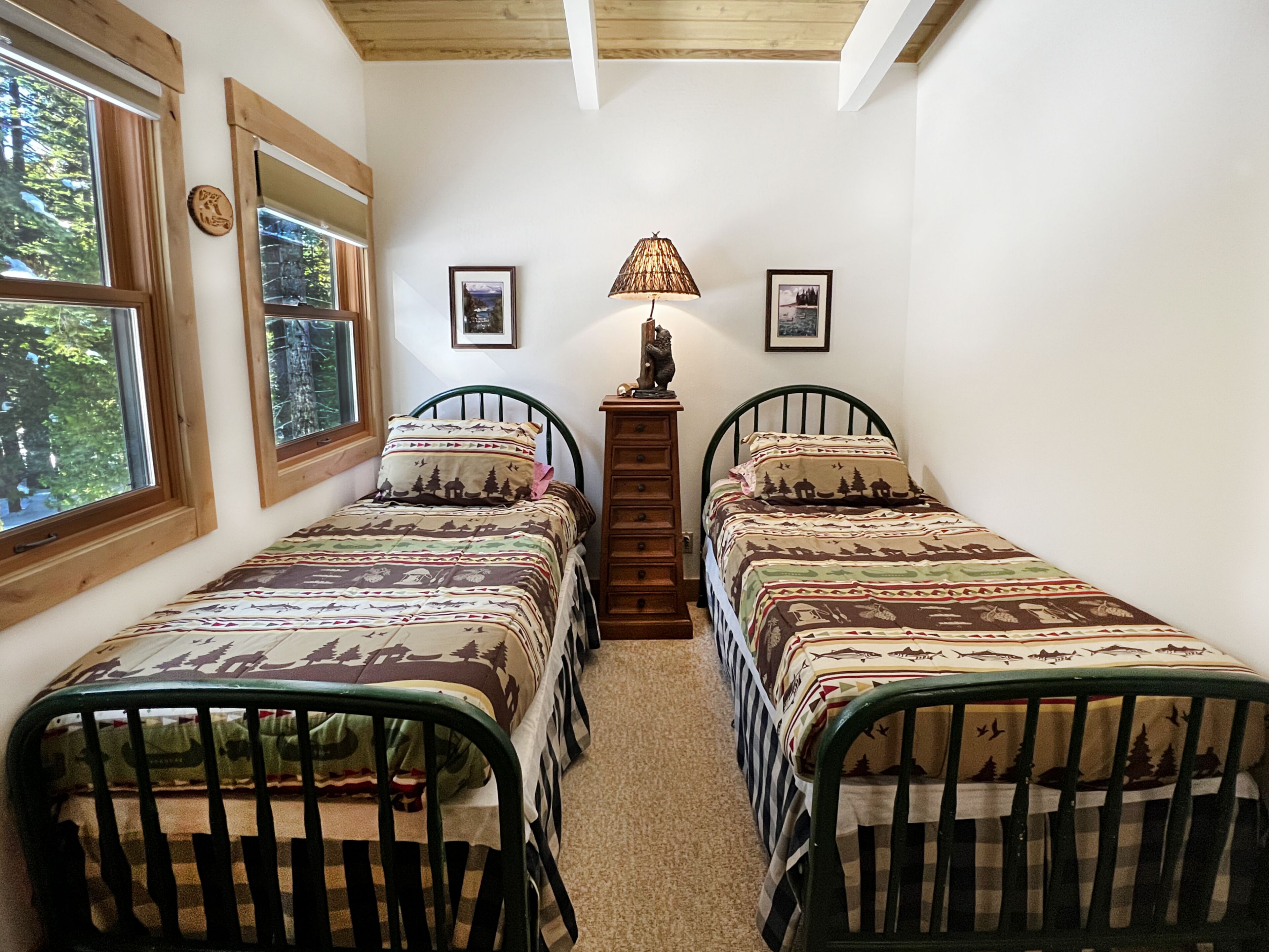 Un dormitorio con dos camas individuales, un aparador de madera, una l ámpara y cuadros en la pared.