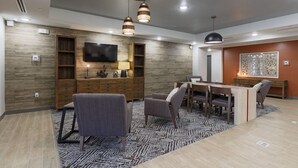 A modern living room with a wooden wall unit, a flat-screen TV, and a dining area with a table and chairs.