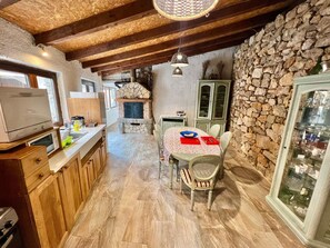 Cozy kitchen with stone fireplace, dining table, and wooden cabinets.