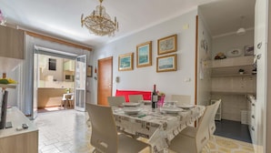 Un comedor con una mesa dispuesta para cuatro, una araña y cuadros en la pared.
