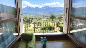 Un balcon donnant sur un paysage montagneux, un banc en bois et deux flacons de gel hydroalcoolique.