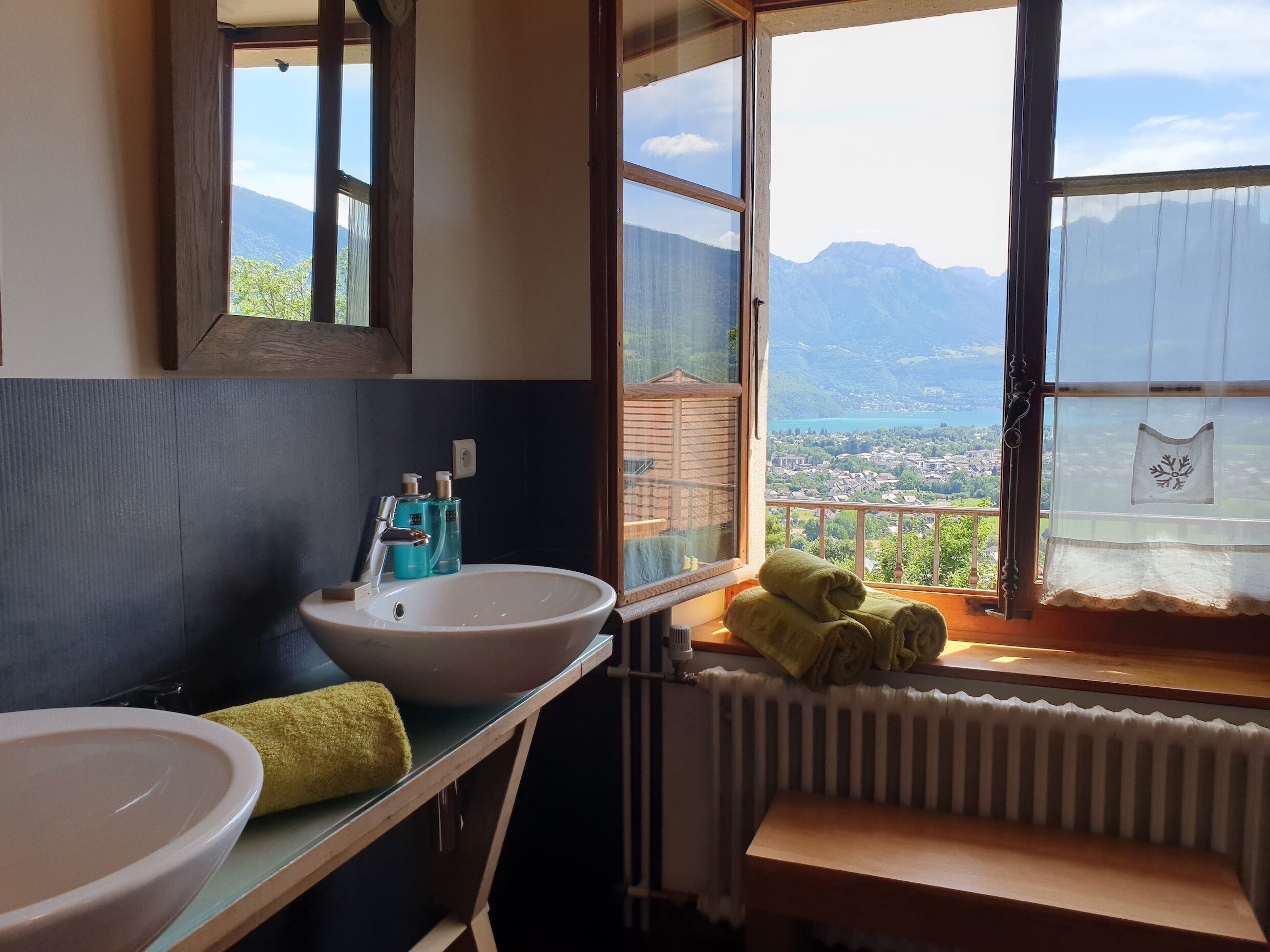 Un baño con lavabo, espejo y ventana con vistas a un paisaje montañoso.