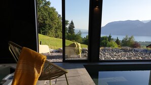 Une chambre moderne dotée d’une grande fenêtre donnant sur un lac et des montagnes.