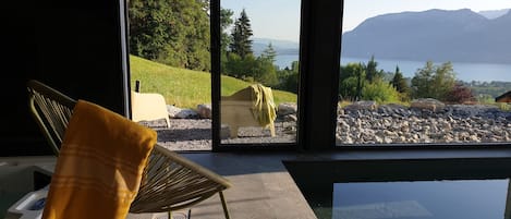 A modern room with a large window overlooking a lake and mountains.