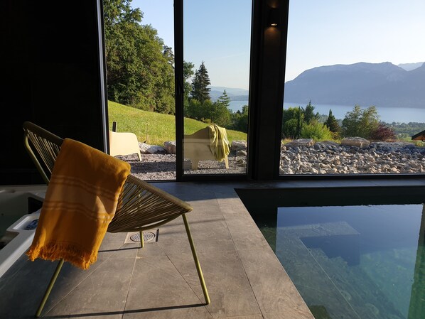 Una habitación moderna con un amplio ventanal con vistas a un lago y montañas.