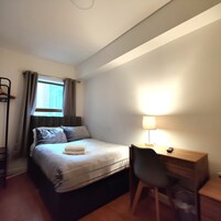 Una habitación de hotel con cama, escritorio, silla y lámpara.