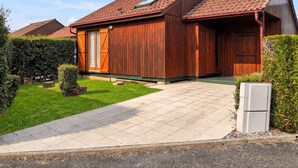 A wooden house with a tiled roof, a front door, and a small front yard.