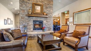 A spacious living area with a stone fireplace, leather sofas, and striped armchairs.