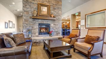 A spacious living area with a stone fireplace, leather sofas, and striped armchairs.