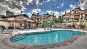 A swimming pool with lounge chairs and a building with multiple balconies in the background.